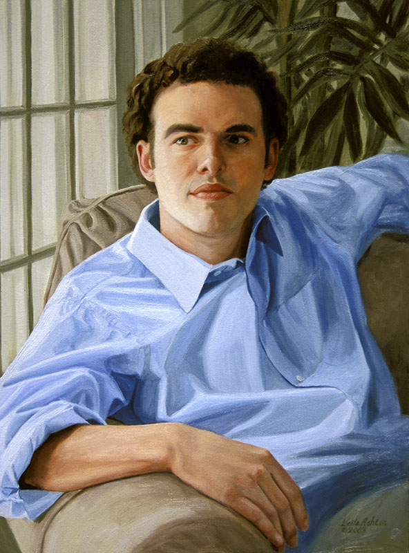 young man in blue shirt seated in front of window